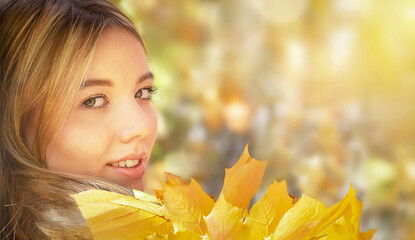 Happy cute smile woman (girl) holding yellow autumn leafs (maple) in the sunny autumnal day....