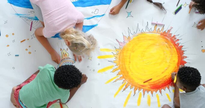 Creative school kids learning together to draw a picture of the earth and space on a sheet of paper from an aerial view. Artistic little boys and girls making an artwork of our solar system.