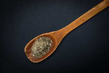 wooden spoon with salt and spices on a dark background
