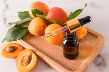 an open bottle with a dropper of cosmetic organic oil apricot on a tray wooden of fruity for face...