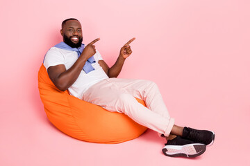 Full body picture of cheery man sit in beanbag promote recommend product shopping sale isolated on...