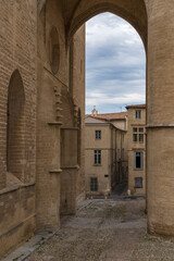 Scenic cityscape view of old cobble street and ancient buildings framed by St Peter's cathedral entrance portal in the historic center of Montpellier city, France