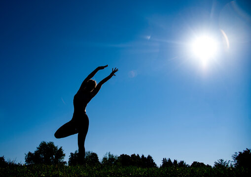 silhouette of a young woman doing yoga in the in the forest at sunrise