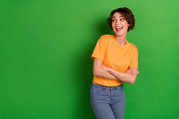 Portrait of impressed positive girl folded arms look interested empty space isolated on green color background