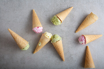 Overhead view of set melting ice cream gelato vanila strawberry pistachio in cones