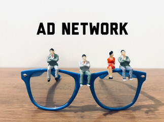 ad network - miniature businessman sitting on top of a pair of glasses