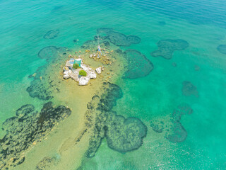 Aerial view of the island close to Notos e Petriti Issos beaches in Corfu, Greece. Small islet with Greek flag and cross near the shore