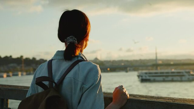 Young tourist with a backpack looking at the city at sunset
