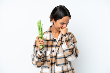 Young hispanic woman holding a green beans isolated on white background having doubts