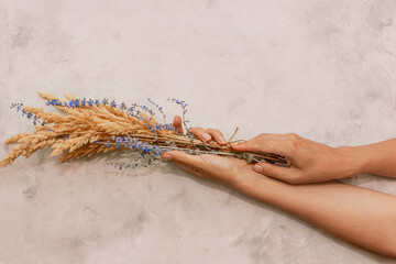 Sensual delicate beige wooden background: delicate dry flower in hands