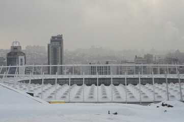 Kyiv, Ukraine. February 17, 2013. Cityscape in winter, snow is falling on the houses and the roof of the stadium. The inscription on the house is a park. Atmospheric haze