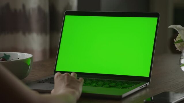 Close up of a caucasian woman hand rest on a laptop computer touchpad with green screen chroma key