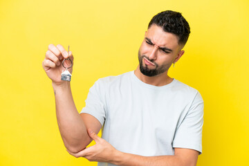 Young Arab man holding home keys isolated on yellow background with sad expression