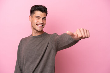 Young caucasian man isolated on pink background giving a thumbs up gesture