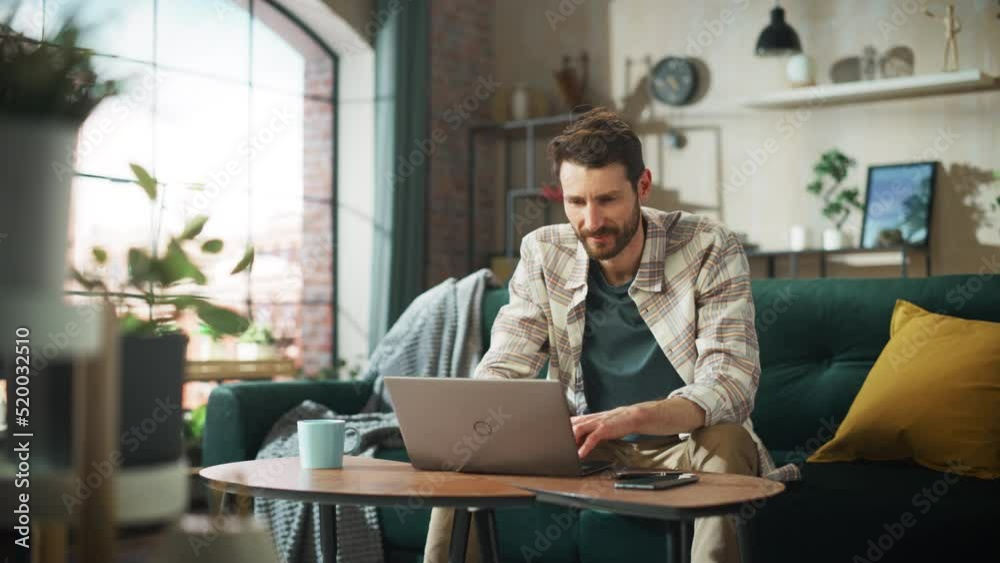 Poster portrait of smiling middle aged man working from home on a laptop computer in sunny cozy apartment. 