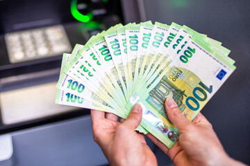 A lot of money in womana lot of money in a woman's hand. Euro banknotes and cach machine in...
