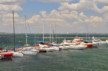 Odessa, Ukraine. July 22, 2021. White yachts on the dock. The sea is emerald green. The city is far away.