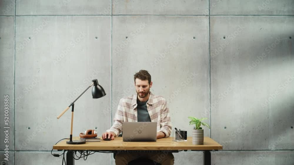 Aufkleber Professional Creative Man Sitting at His Desk in Office Working on a Laptop Computer, Working, Thinking, Solving Problems and Smiling at Success. Stylish Office Space Design Perfect for Productivity
