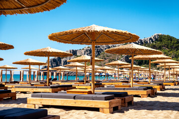Loungers under sunshades ready for vacationers in Tsambika beach at Rhodes island in Greece