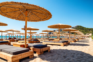 Loungers under sunshades ready for vacationers in Tsambika beach at Rhodes island in Greece