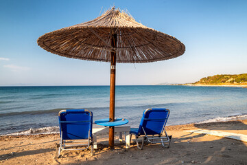 Loungers under sunshades ready for vacationers in west coast of Rhodes island in Greece