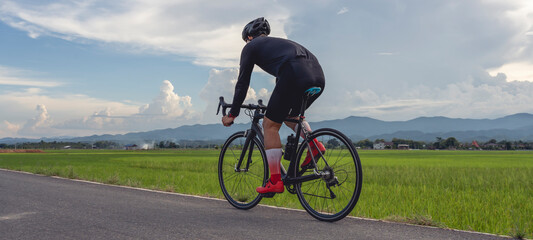 Professional cyclist in cycling training suit against green nature blur background Healthy fitness and lifestyle concepts.
