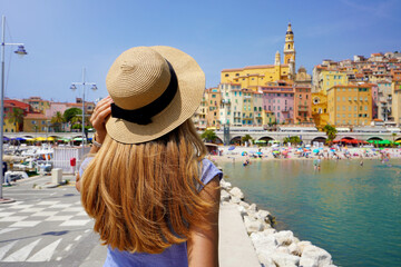 Summer holiday in France. Back view of young woman with long hair and hat in Menton, French Riviera.