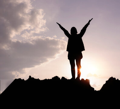 Silhouette of a woman praying over a beautiful sky. Hypnosis concept.