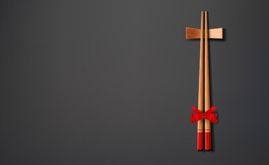 Chopsticks and chopstick holder, decorated with red bow lie on a gray background.
