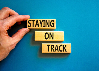 Staying on track symbol. Concept words Staying on track on wooden blocks on a beautiful blue background. Businessman hand. Business, motivational and staying on track concept. Copy space.