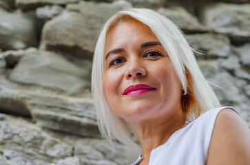Cute woman portrait with white hair on the background of an old stone wall