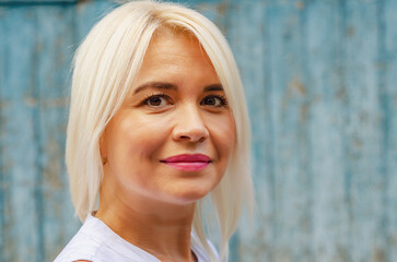 Portrait of a middle-aged beautiful cheerful woman on a wooden wall background. Success, antiaging