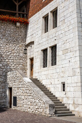 Biały średniowieczny budynek z kamienia. Wejście do budynku po kamiennych schodach.