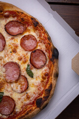 Homemade Pepperoni, Salami Pizza with basil, tomatoes, cheese on wooden table. ready to eat