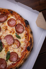 Homemade Pepperoni, Salami Pizza with basil, tomatoes, cheese on wooden table. ready to eat
