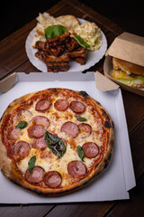 Homemade Pepperoni, Salami Pizza with basil, tomatoes, cheese on wooden table. ready to eat