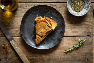 Part de tarte tatin à l'oignon huile d'olive et romarin fait maison sur table en bois