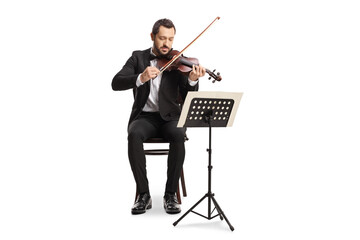 Full length portrait of an elegant man sitting and playing a violin with a music stand