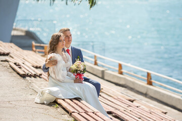 a young man in a suit and a girl in a wedding dress are on the seashore