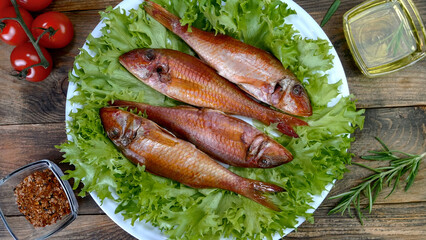 Smoked whole sea fish served salad leaves with vegetable and spices on white dish. - 520039530
