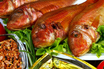 Smoked whole sea fish served salad leaves with vegetable and spices on white dish. - 520039532