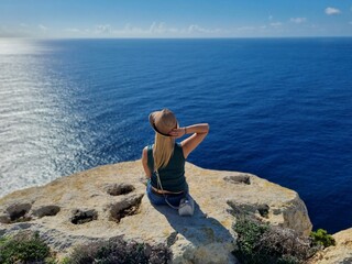 woman sitting on a cliff on Gozo island