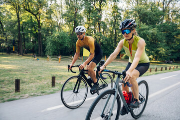 Couple riding road bicycles outside and wearing helmets and sunglasses