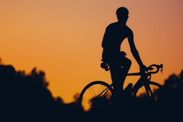 Silhouette of an athletic man in sport clothes riding a bike in the nature