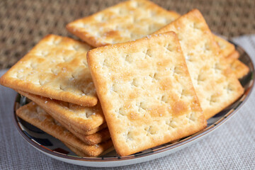 A pile of dry, thin crackers in a cup. Natural light.