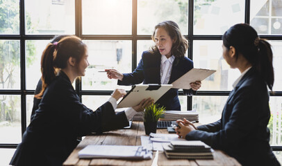 Business meeting. The senior manager talks to employees in the conference room and discuss company project development strategies during the meeting.