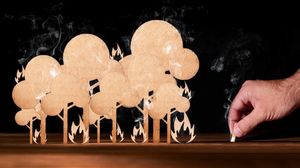 Forest of cardboard cutout burning and a hand with a badly extinguished cigarette butt. Risk of...