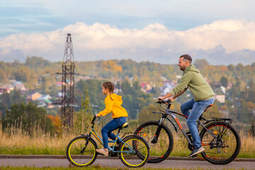 Happy father and daughter take bike ride in nature in autumn.