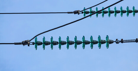Close up of a transparent turquoise high voltage insulator or isolator in sunlight on electric...