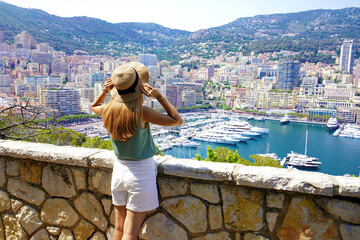 Beautiful stylish girl enjoying view of Monte-Carlo cityscape with skyscrapers and yachts in the...